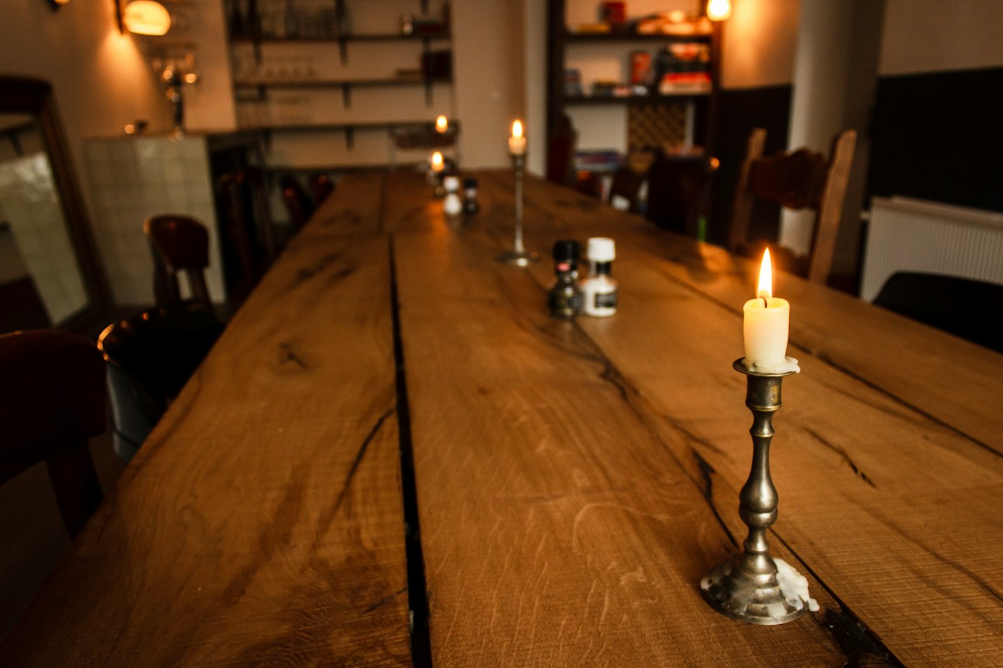Candele accese su un tavolo da pranzo rustico in legno.